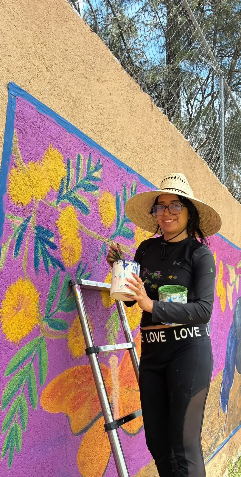 Artista pintando un mural colorido del proyecto La Vida de Las Cachinches en San Miguel de Allende